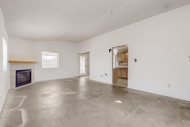 unfurnished living room with lofted ceiling, a fireplace, and concrete flooring