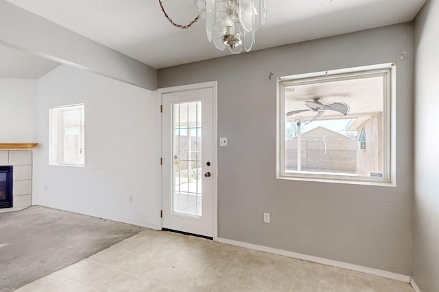 entryway with a tiled fireplace, plenty of natural light, and baseboards