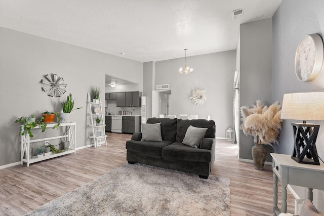 living area with a chandelier, visible vents, baseboards, and light wood-style floors