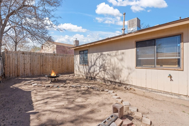 exterior space with a fire pit, central AC, and fence