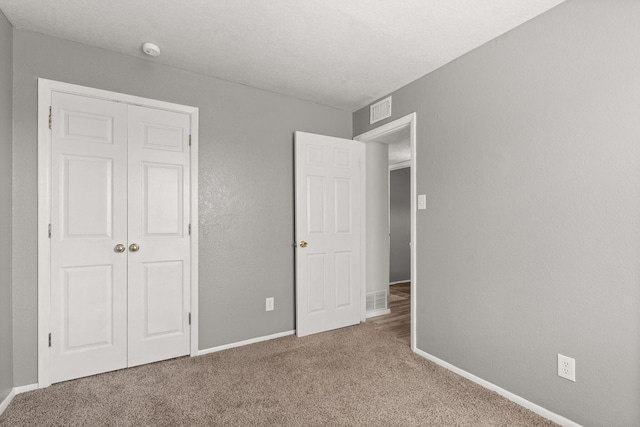 unfurnished bedroom with a closet, visible vents, carpet flooring, and baseboards