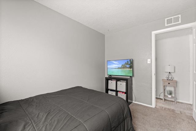 carpeted bedroom featuring baseboards, visible vents, and a textured ceiling