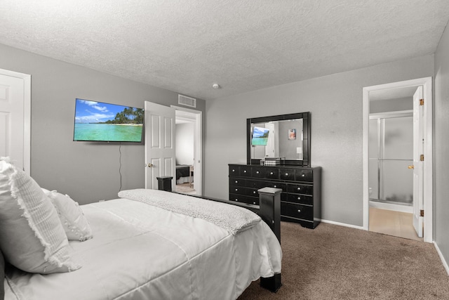 carpeted bedroom with visible vents, ensuite bathroom, and a textured ceiling