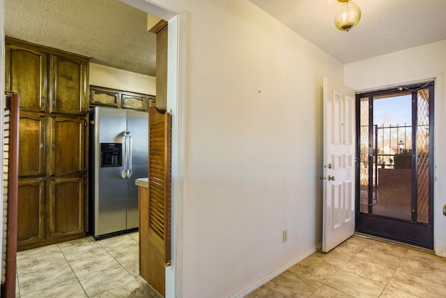 interior space with light tile patterned floors, a textured ceiling, and baseboards