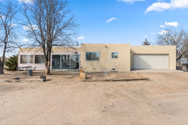 rear view of property featuring crawl space, stucco siding, driveway, and a garage