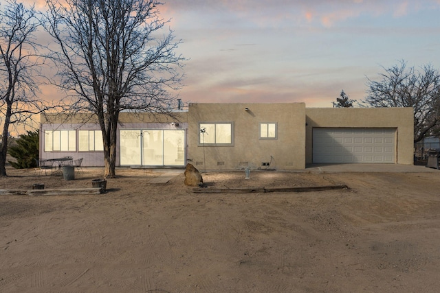 view of front of home featuring stucco siding, a garage, and dirt driveway