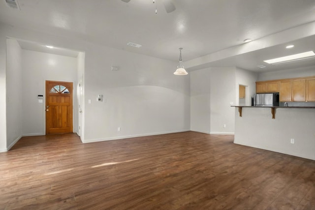 unfurnished living room featuring visible vents, baseboards, ceiling fan, and dark wood-style flooring