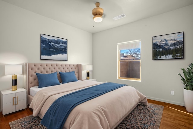 bedroom with ceiling fan, wood finished floors, visible vents, and baseboards