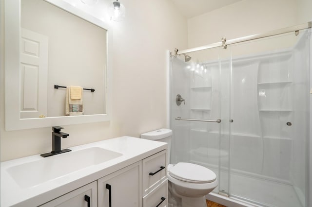 full bathroom with a stall shower, toilet, and vanity