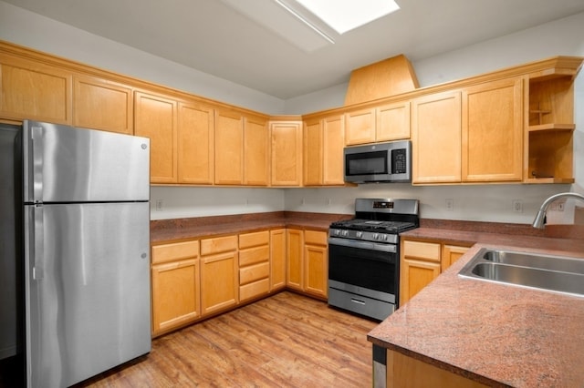 kitchen with light brown cabinets, a sink, open shelves, appliances with stainless steel finishes, and light wood finished floors