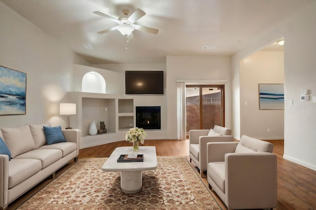 living room with ceiling fan, visible vents, baseboards, and wood finished floors