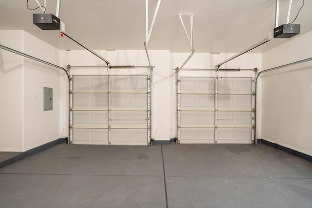 garage featuring electric panel, a garage door opener, and baseboards