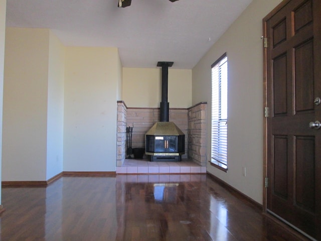 unfurnished living room with a healthy amount of sunlight, wood finished floors, and a wood stove