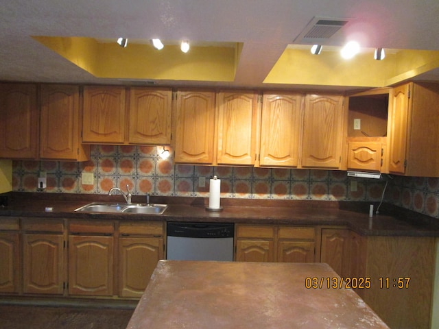 kitchen with dishwashing machine, visible vents, a sink, a raised ceiling, and backsplash