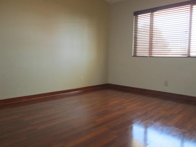 unfurnished room featuring baseboards and dark wood-style flooring