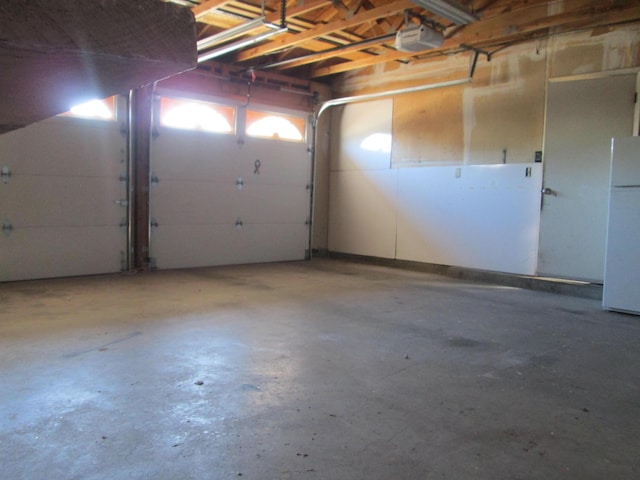 garage with a garage door opener and freestanding refrigerator