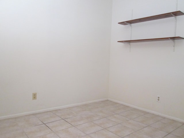 unfurnished room featuring baseboards and light tile patterned flooring