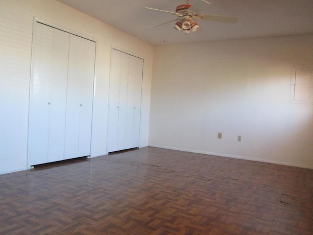 unfurnished bedroom with baseboards, multiple closets, and ceiling fan