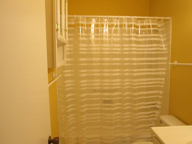 full bath featuring a shower with shower curtain, toilet, and vanity