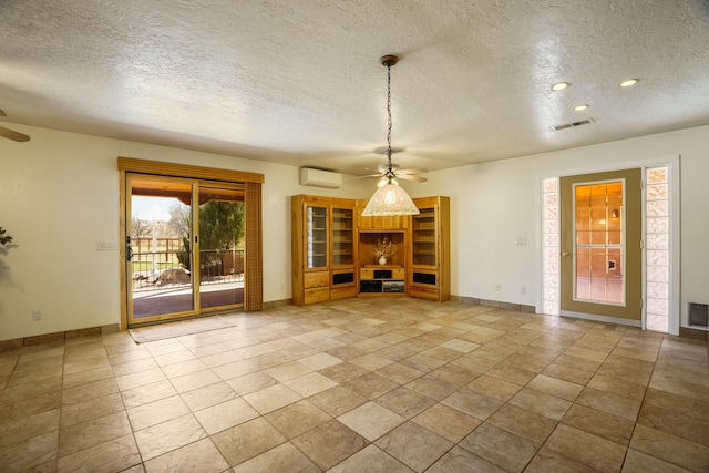 unfurnished living room with visible vents, baseboards, ceiling fan, and a wall mounted AC