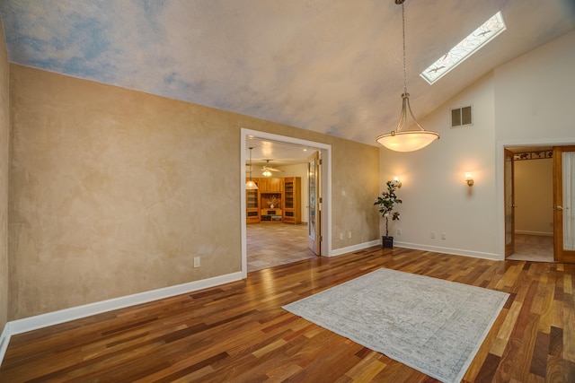 empty room with visible vents, a skylight, baseboards, and wood finished floors