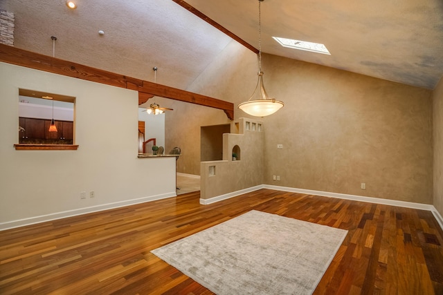 unfurnished living room with ceiling fan, a skylight, baseboards, and wood-type flooring