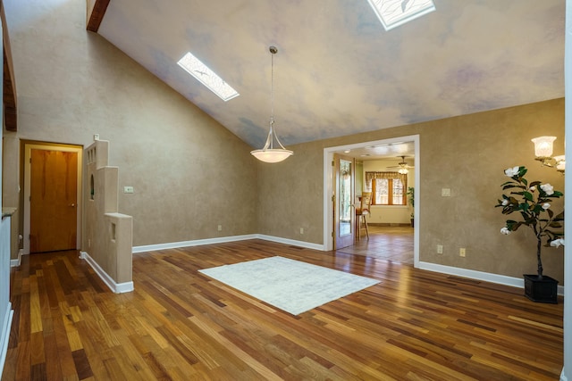 unfurnished dining area featuring high vaulted ceiling, a skylight, baseboards, and wood finished floors