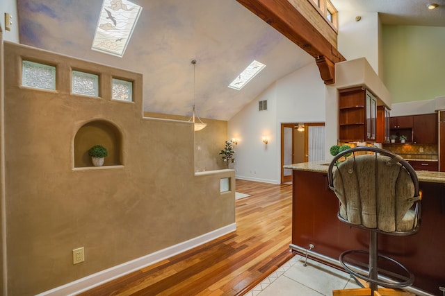 interior space featuring visible vents, beam ceiling, light wood-style flooring, a skylight, and open shelves