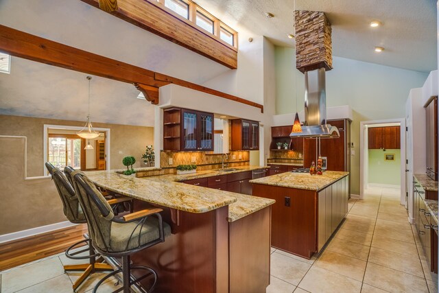 kitchen featuring open shelves, beam ceiling, a peninsula, island range hood, and a sink