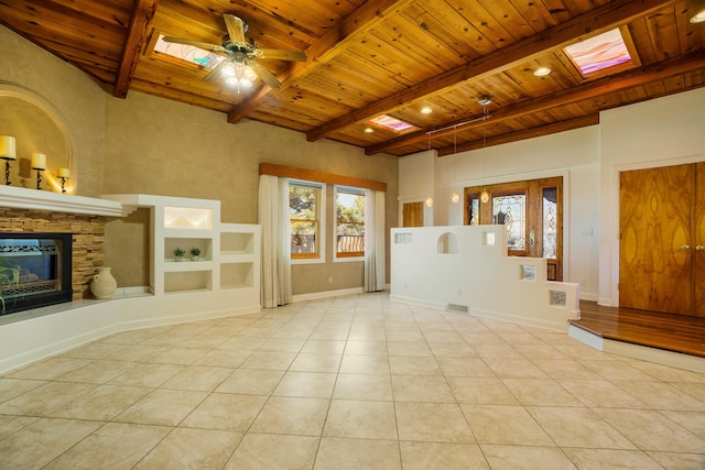 unfurnished living room featuring beamed ceiling, wood ceiling, light tile patterned floors, a fireplace, and a skylight