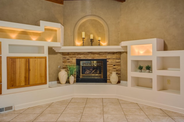 interior space featuring tile patterned floors, visible vents, built in shelves, and a glass covered fireplace