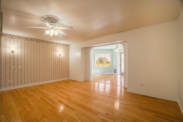 empty room featuring a ceiling fan, baseboards, and light wood finished floors