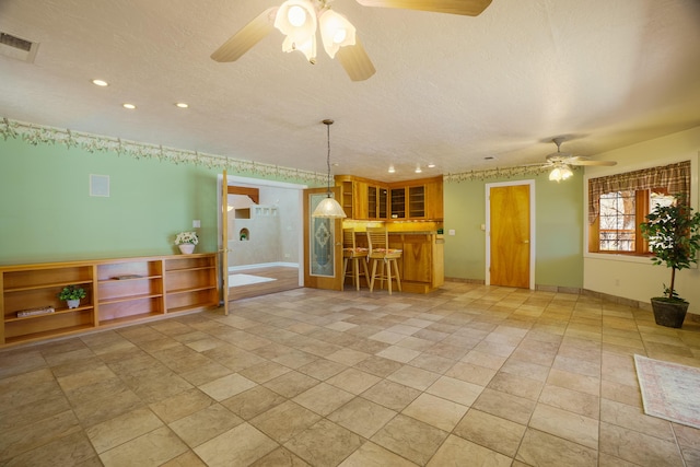 interior space with visible vents, a ceiling fan, a textured ceiling, recessed lighting, and baseboards