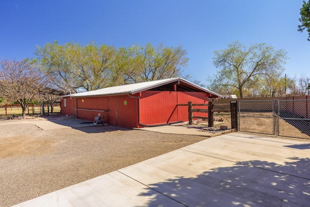 exterior space with metal roof, fence, an outdoor structure, and a gate