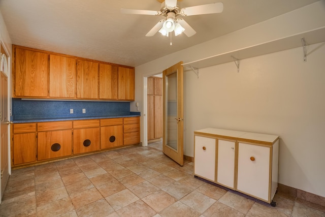 kitchen with baseboards, brown cabinets, backsplash, and a ceiling fan