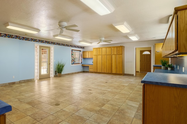 unfurnished living room featuring a textured ceiling, baseboards, and ceiling fan