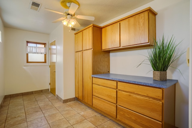 kitchen with visible vents, baseboards, dark countertops, and a ceiling fan