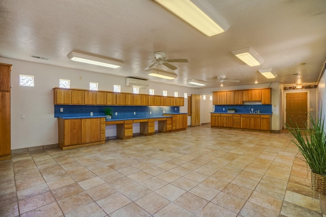 kitchen featuring visible vents, decorative backsplash, brown cabinets, a ceiling fan, and a sink