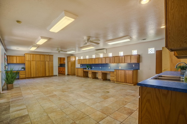 kitchen featuring tasteful backsplash, dark countertops, ceiling fan, brown cabinetry, and a sink