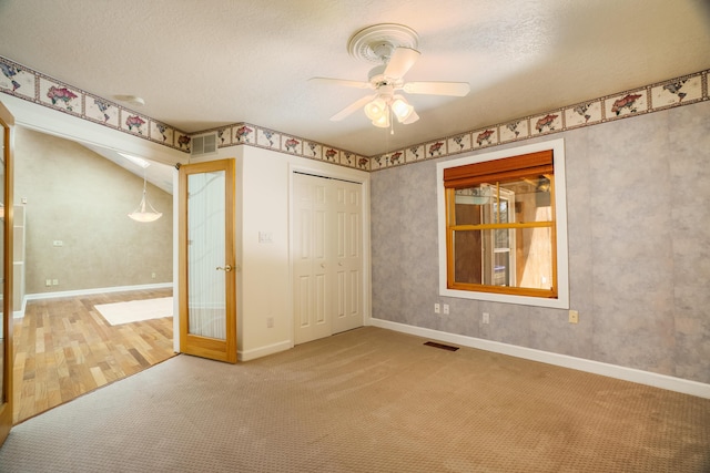 unfurnished bedroom featuring a ceiling fan, carpet, visible vents, and a closet