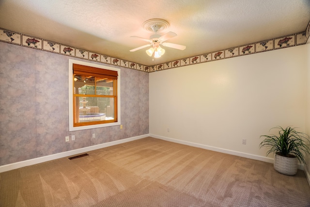 carpeted empty room with visible vents, baseboards, a textured ceiling, and a ceiling fan