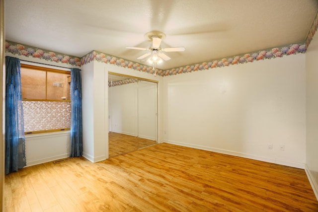 unfurnished bedroom with a ceiling fan, visible vents, baseboards, light wood-style floors, and a closet