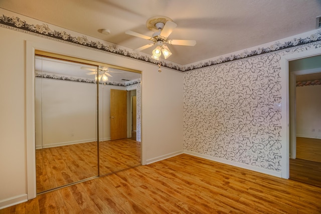 unfurnished bedroom featuring wood finished floors, visible vents, baseboards, ceiling fan, and a closet