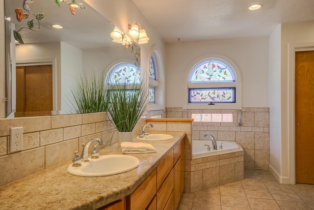 full bathroom with tile patterned floors, double vanity, a garden tub, and a sink