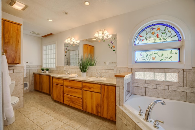 full bathroom with a sink, tile walls, a bath, and double vanity