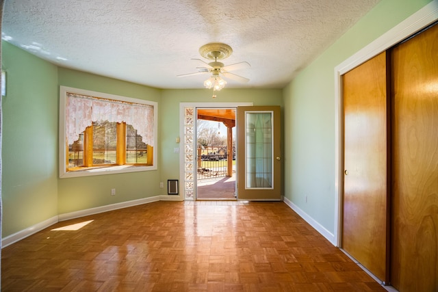 doorway to outside with baseboards, a textured ceiling, and ceiling fan