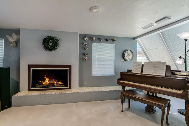 sitting room featuring carpet floors, a warm lit fireplace, and a textured ceiling