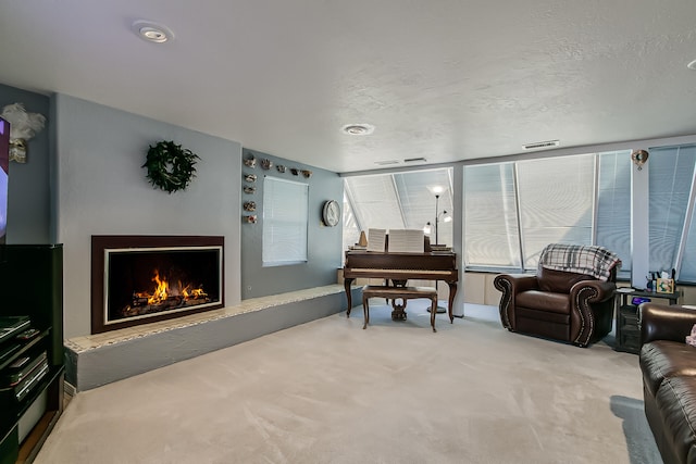 carpeted living area featuring visible vents, a warm lit fireplace, and a textured ceiling