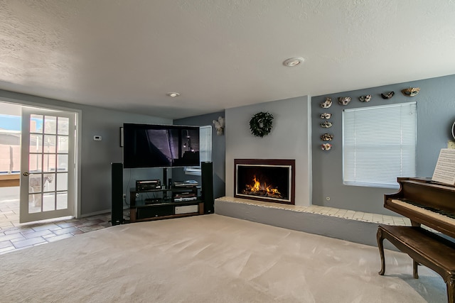 carpeted living area with a textured ceiling and a lit fireplace