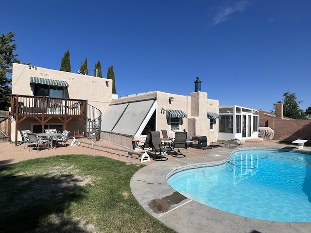 outdoor pool featuring fence, outdoor dining area, a sunroom, a patio, and a diving board